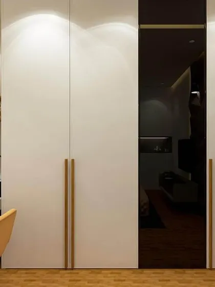 A bedroom design that combines functionality with style, featuring a sleek white wardrobe with a dark glass accent panel. The adjacent study nook is well-lit and includes open shelving for easy access to books and decor.