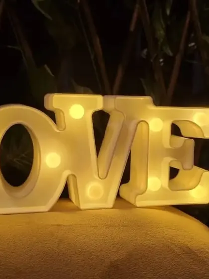 A close-up of the 'LOVE' marquee letters, a popular add-on for anniversaries, proposals, and romantic date nights. The warm light adds a beautiful glow to the room.