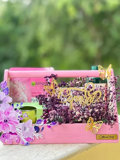 This "little box of self-care" is a perfect pampering gift. The pink wooden caddy is filled with grooming essentials like a face mask and a scented candle, decorated with beautiful purple flowers.