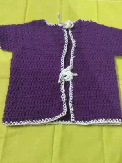 The purple baby cardigan shown open to display the delicate white trim and tie closure.