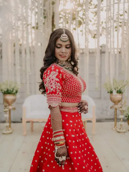 A full-length view of the bride against a beautiful floral backdrop. The glam makeup and open hairstyle create a breathtaking portrait that every bride dreams of.
