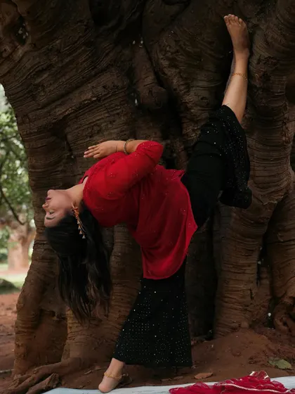 A creative standing split variation against a tree, playing with balance and flexibility.
