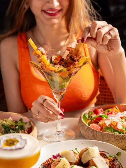 A guest enjoying a shrimp cocktail at Blah Bombay. The bright colors and happy expression create an inviting and appetizing image.