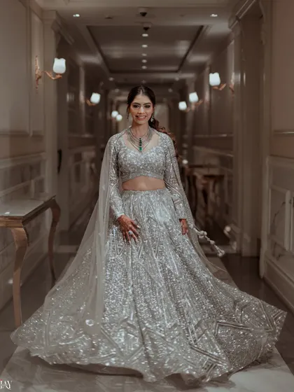 A full-length shot of the bride smiling, her silver lehenga sparkling from head to toe.