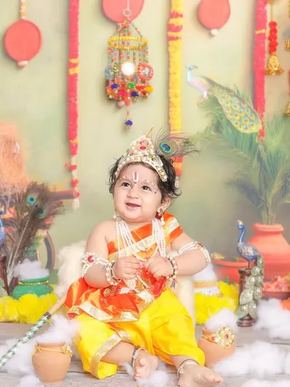 Another angle of our little Krishna, showing the full, vibrant set design with hanging bells and peacocks.