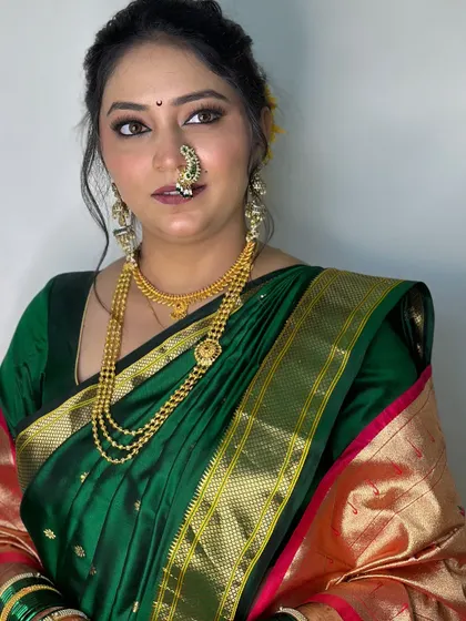 A classic portrait of the bride in her green Paithani saree, showcasing the flawless base makeup and soft contouring.