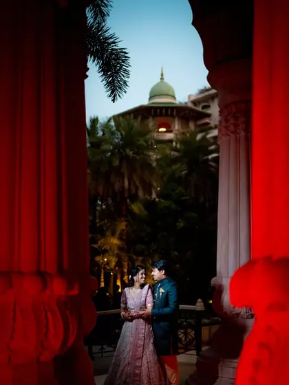 A dramatic and romantic reception photo, framed by red pillars, capturing the couple in an intimate moment.