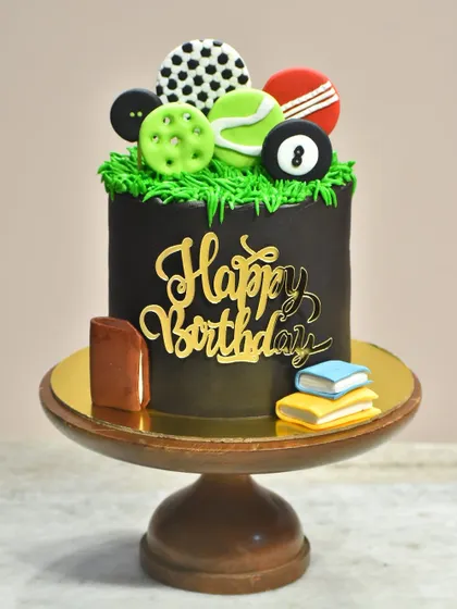 A unique cake for someone who loves both sports and books. This design features a variety of fondant sports balls on top and miniature edible books at the base.