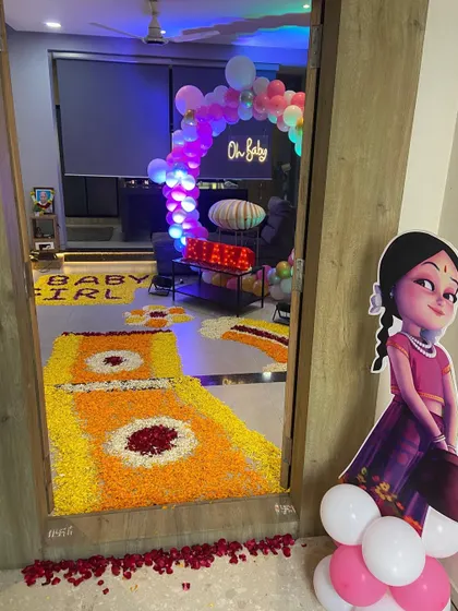 The entrance to a home decorated for a 'Welcome Baby' celebration, featuring a flower rangoli path.