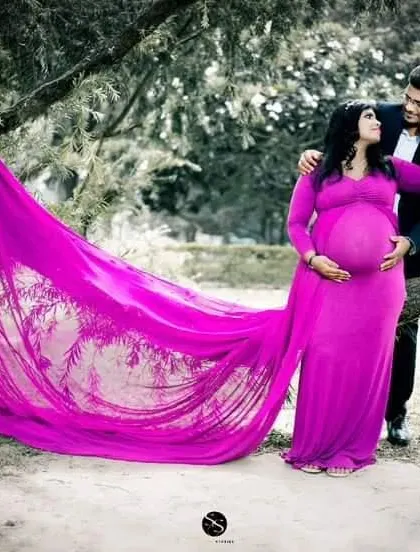 This magenta A-line gown with a long, flowing trail creates a stunning visual in this outdoor shot. The vibrant color and dramatic fabric make for a truly memorable photo.