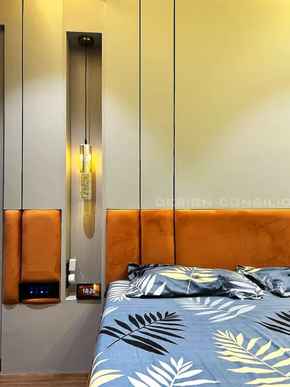 This shot highlights the custom headboard in a vibrant orange fabric and the unique hanging pendant light. The niche in the wall paneling serves as a perfect spot for a bedside lamp and charging station.