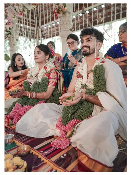 A candid moment during the wedding ceremony, with the couple seated and surrounded by family, their expressions full of happiness.