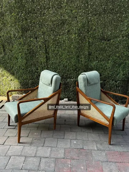 The chairs are set against a green hedge, highlighting their natural materials and calming color palette.