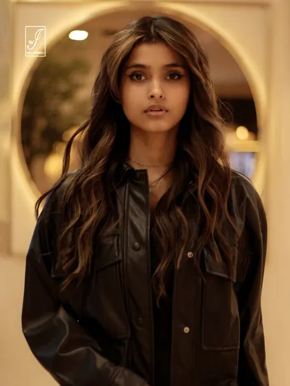 A direct and engaging portrait, framed by a circular light element in the background, which adds depth and visual interest.
