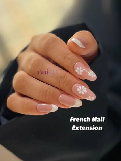 The perfect example of a classic French extension with a little something extra. This look pairs timeless white tips with delicate white daisy accent nails.