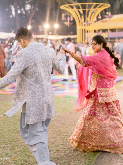 The couple dances joyfully at their Mehendi ceremony, a candid moment of fun and celebration.