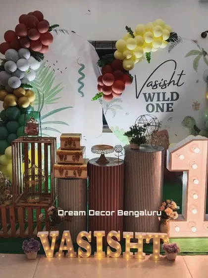 A 'Wild One' dinosaur-themed party. We used a mix of green, yellow, and maroon balloons with dinosaur cutouts and rustic wooden crates to create a prehistoric jungle vibe.