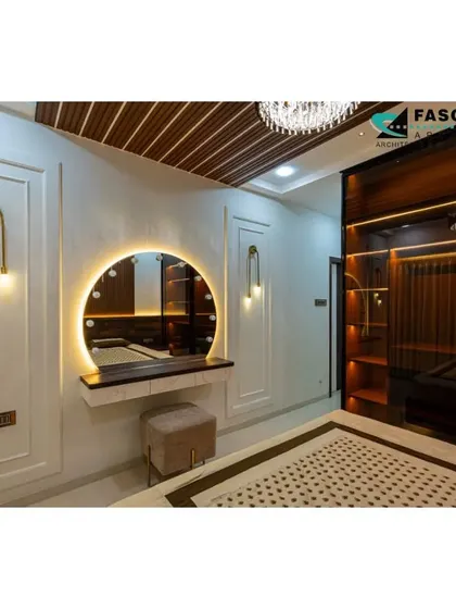 A glamorous bedroom featuring a large, round vanity mirror with studio lighting, perfect for getting ready. The design includes elegant wall paneling, artistic light fixtures, and a dark wood wardrobe with internal lighting.