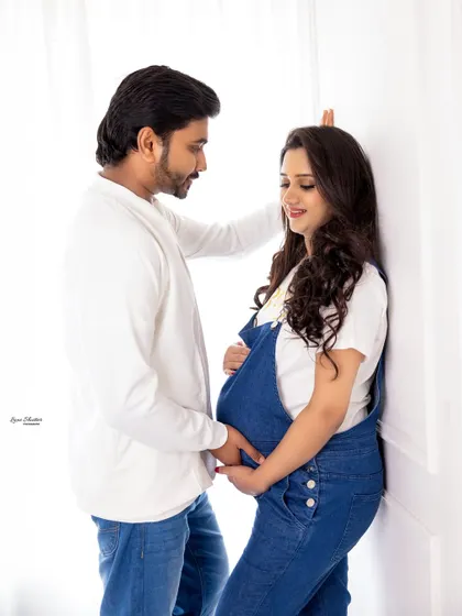 An intimate moment from a casual maternity shoot. The simple, coordinated outfits keep the focus on the couple's connection and the beautiful baby bump.