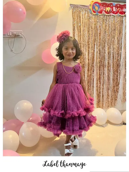 A happy birthday girl in her magenta party frock with a matching hair accessory.