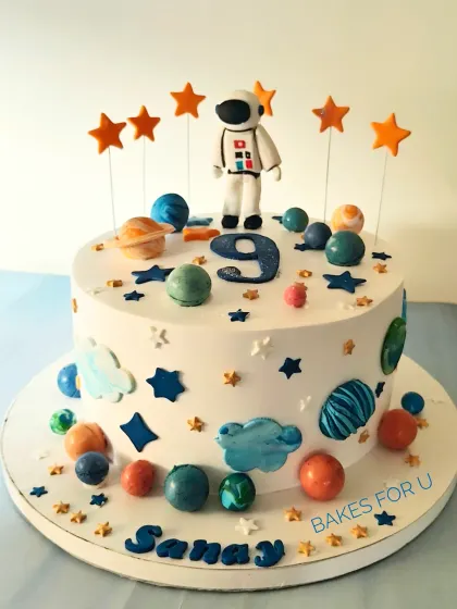 A solar system cake perfect for a budding astronaut. This design is decorated with edible planets, stars, and an astronaut figure, making learning about space delicious and fun.