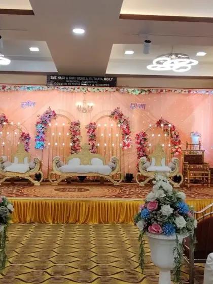 A traditional stage setup for a Maharashtrian wedding at Devadiga banquet hall. The decor features multiple golden chairs for family rituals and a colorful floral backdrop, keeping the focus on the ceremony.
