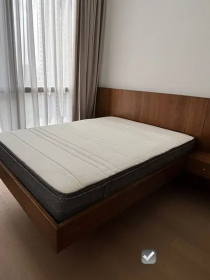 A minimalist floating bed design with an extended headboard that incorporates a built-in side table. This custom piece is perfect for creating a clean, uncluttered look in a modern bedroom.