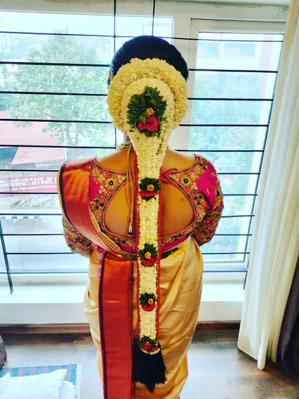 A beautiful floral 'Jadai' made of fresh jasmine, with red and green floral accents for a pop of color.