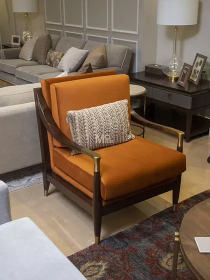 The Lusso Armchair, featured in a sophisticated Delhi NCR residence. This piece makes a statement with its bold burnt orange velvet, sleek wooden frame, and brass-tipped armrests for a refined touch.