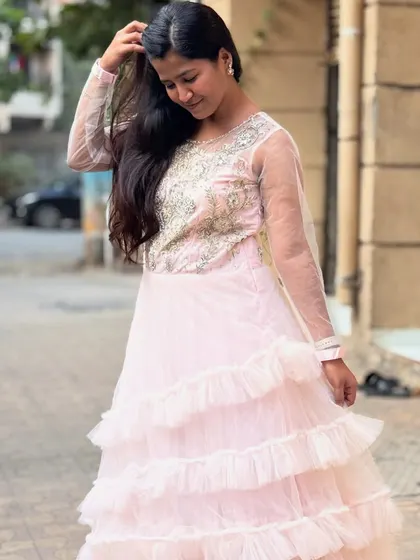 This baby pink tiered gown with an embroidered bodice is a soft and romantic choice for any party. The ruffles add a playful touch.