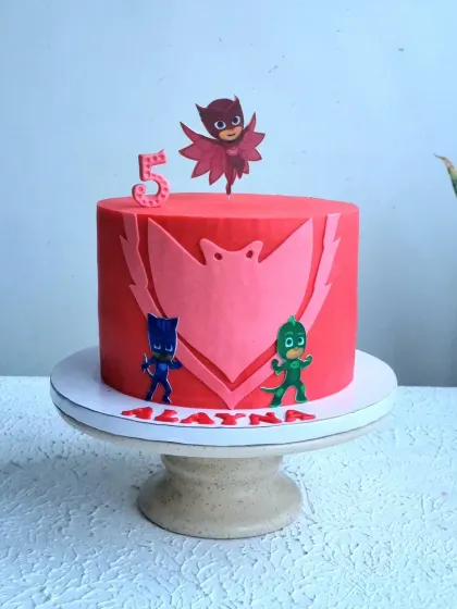 A full view of the red PJ Masks cake on its stand.