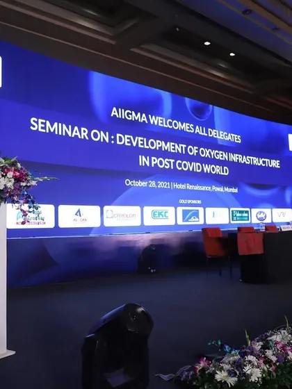 A professional setup for a corporate seminar on post-covid infrastructure. The stage features a large, branded LED screen and a panel seating area, designed for clarity and impact.