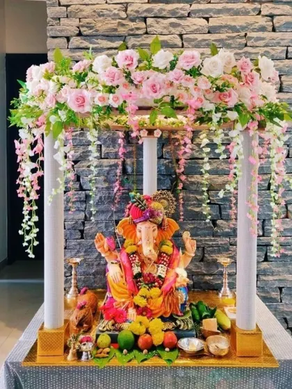 This elegant four-poster mandap is adorned with pink and white flowers and hanging floral strings. It's a simple yet sophisticated design, perfect for modern homes.