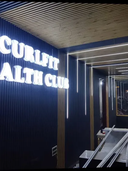 I also specialize in commercial interiors, like this project for Curlfit Health Club. I used a combination of dark WPC louvers for the walls and lighter wooden-finish panels for the ceiling to create a modern and energetic vibe. The backlit 3D signage adds a professional finishing touch.