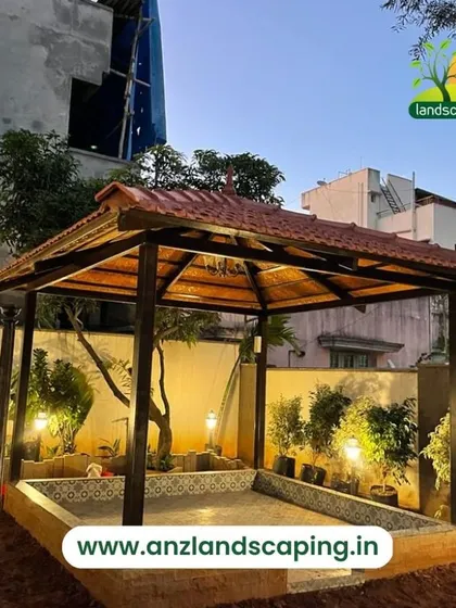 A traditional tile-roofed gazebo provides a charming focal point in this garden. The structure is illuminated with warm lighting, creating a perfect evening retreat.