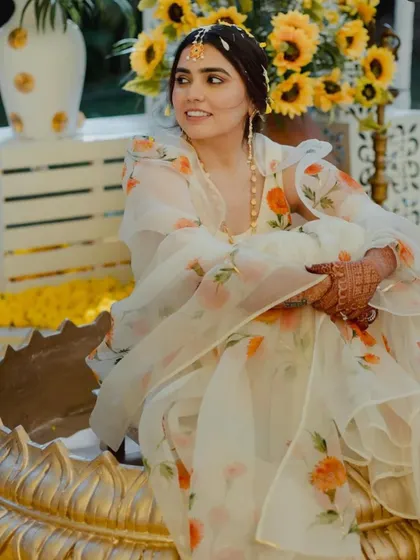 The bride looking radiant and happy during her Haldi ceremony, seated against a backdrop of beautiful sunflowers.