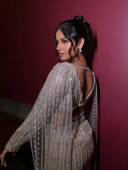A view from the back, showcasing the elegant updo that complements the glamorous makeup and open-back outfit. The complete look is chic and sophisticated.