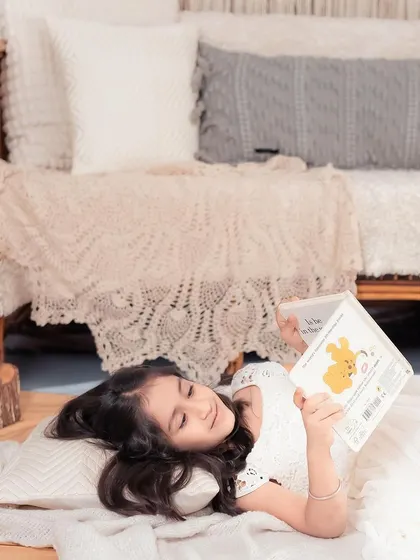 Sometimes the best moments happen when a child is lost in their own little world. Here, a young girl enjoys a storybook in our cozy studio corner.