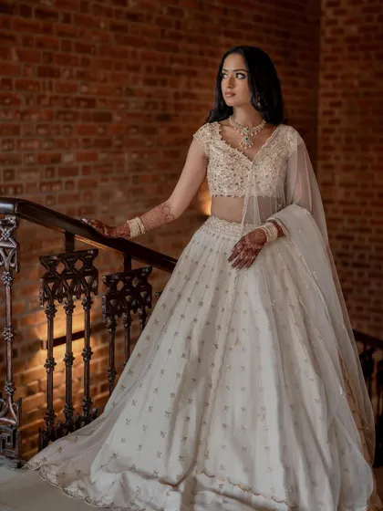 A stunning bride in a white lehenga, exuding grace and elegance. We use creative framing and lighting to capture a variety of beautiful portraits.