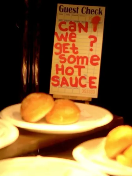 A fun detail from the burger station setup, with a sign that reads "Can we get some hot sauce?" adding a touch of humor and personality.