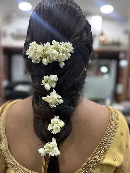 A thick, voluminous braid decorated with fresh jasmine flowers. This is a timeless and elegant hairstyle for any traditional Indian function.