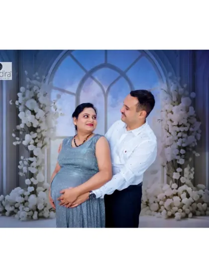 An intimate studio portrait of the couple embracing, both looking at each other with love as they hold the baby bump.