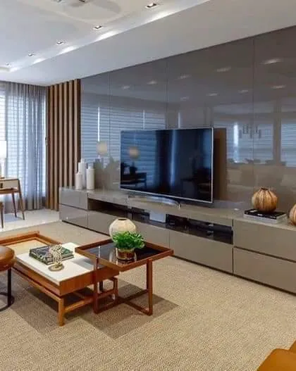 A full wall of glossy grey panels makes this TV unit a stunning focal point. The low, wide console offers extensive storage, and the clean lines are perfect for a contemporary home.