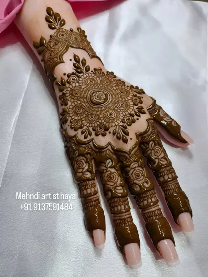 Another view of the mandala design on a practice hand. This angle highlights the detailed work on the fingers, where each segment has a unique pattern that complements the main design.