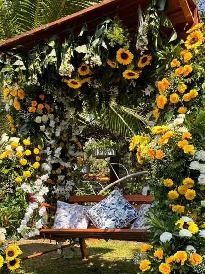 A charming floral swing for a Haldi or Mehendi event, lavishly decorated with sunflowers, marigolds, and white blooms, creating a perfect photo spot.