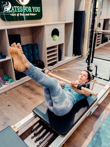 This client uses the push-through bar on the Reformer for a C-curve exercise, which deeply articulates the spine and strengthens the abdominal muscles.