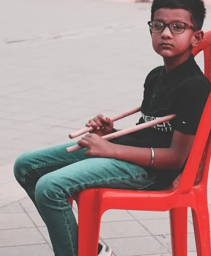 A young drummer waits patiently for his turn to perform. The discipline and focus required for live shows are an important part of the learning process.