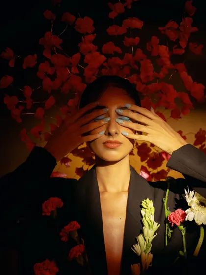 An expressive and artistic portrait using flowers as a central theme. The pose and lighting create a sense of introspection and beauty.