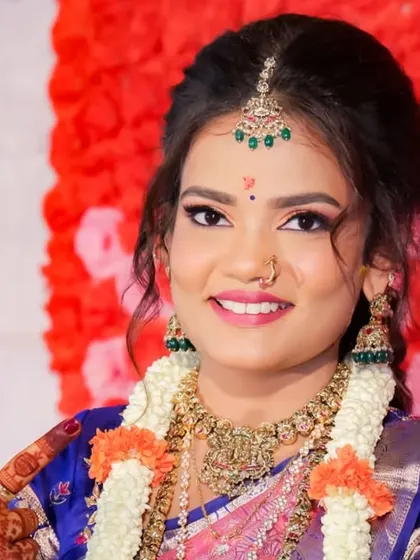 A close-up bridal portrait that captures her bright smile and the fine details of her makeup and jewelry against a vibrant floral background.