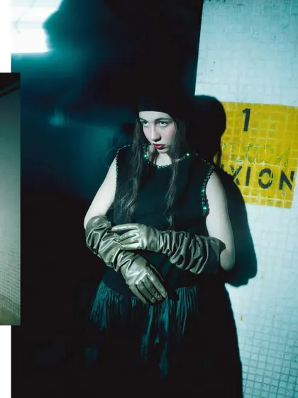 A portrait using harsh shadows and a cool, blue-green light. The model is partially obscured by darkness, creating a sense of mystery and intrigue.